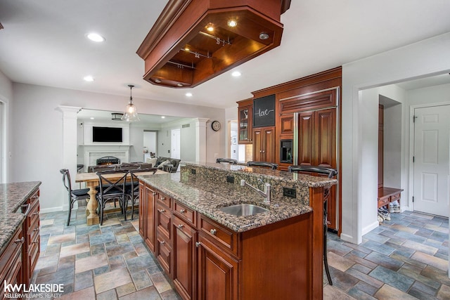 25986 Glenmoor St, Novi, MI 48374 - kitchen featuring decorative columns, stone finish floors, a breakfast bar, an island with sink, and recessed lighting