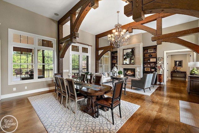 2940 Buell Rd, Oakland Twp, MI 48363 - dining space featuring wood finished floors, a chandelier, high vaulted ceiling, a warm lit fireplace, and arched walkways