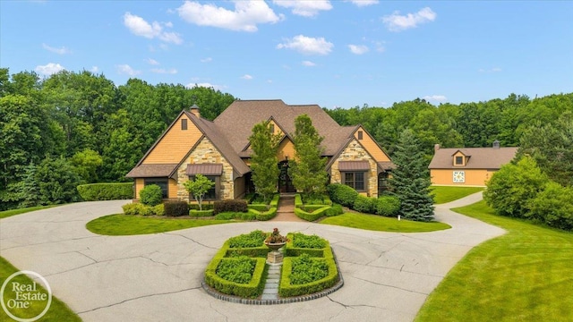 2940 Buell Rd, Oakland Twp, MI 48363 - craftsman-style house featuring stone siding, curved driveway, a front yard, and a chimney