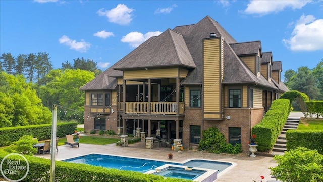 2940 Buell Rd, Oakland Twp, MI 48363 - rear view of house with brick siding, a patio, a shingled roof, stairway, and a pool with connected hot tub