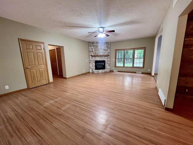 876 N Sanford Ln, Au Gres, MI 48703 - unfurnished living room with a ceiling fan, light wood-style floors, a textured ceiling, and a fireplace