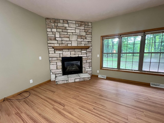 876 N Sanford Ln, Au Gres, MI 48703 - unfurnished living room featuring a stone fireplace, wood finished floors, and a textured ceiling