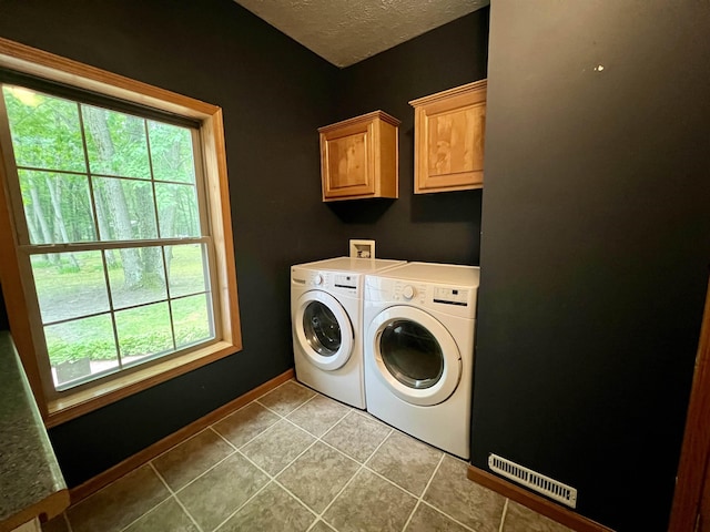 876 N Sanford Ln, Au Gres, MI 48703 - laundry room with washing machine and dryer, cabinet space, a textured ceiling, and tile patterned floors