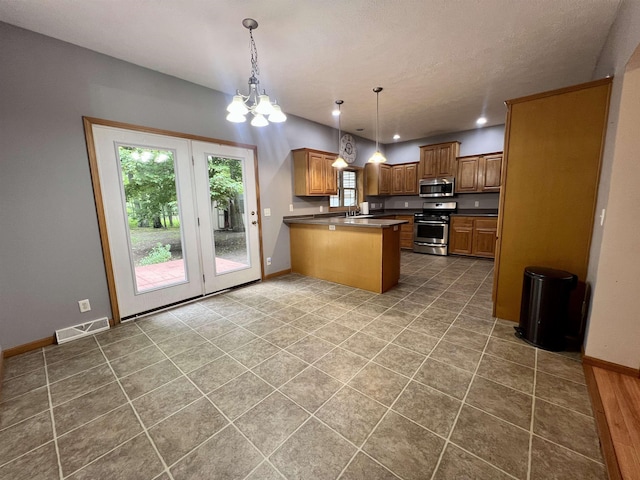 876 N Sanford Ln, Au Gres, MI 48703 - kitchen with appliances with stainless steel finishes, a peninsula, dark countertops, brown cabinetry, and a chandelier