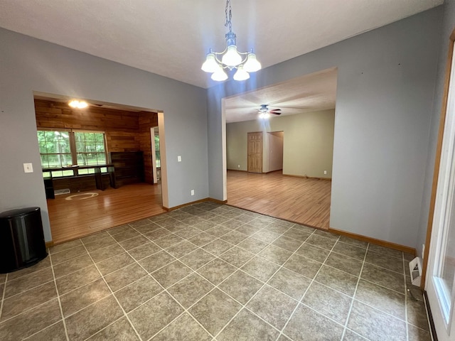 876 N Sanford Ln, Au Gres, MI 48703 - spare room with tile patterned flooring, a chandelier, a ceiling fan, and wooden walls
