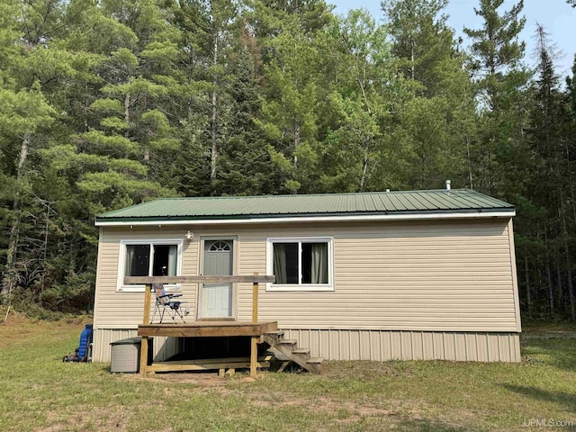 E8310 County Road 440th Hwy, Wetmore, MI 49895 - view of front facade with a wooden deck, a front yard, a forest view, and a metal roof