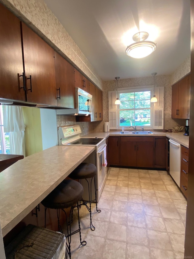1782 Hollywood St, Grosse Pointe Woods, MI 48236 - kitchen with white appliances, light countertops, hanging light fixtures, a peninsula, and a breakfast bar area