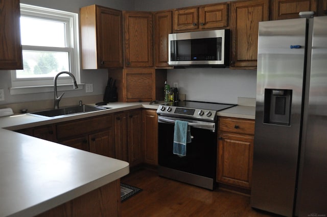 9180 Woodridge Dr, Davison, MI 48423 - kitchen featuring appliances with stainless steel finishes, light countertops, dark wood-type flooring, and brown cabinetry