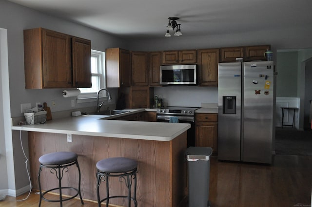 9180 Woodridge Dr, Davison, MI 48423 - kitchen with appliances with stainless steel finishes, a peninsula, light countertops, light wood finished floors, and a breakfast bar