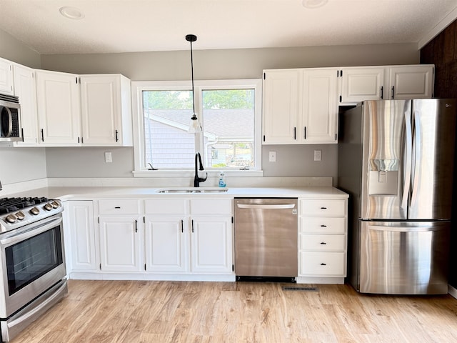 3331 Lakeshore Dr, Gladwin, MI 48624 - kitchen with stainless steel appliances, white cabinets, light wood finished floors, and light countertops