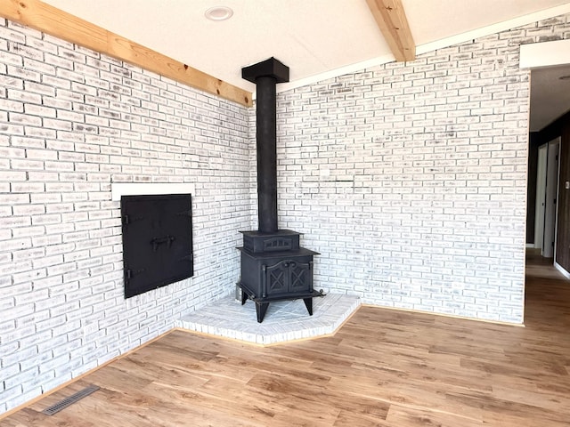 3331 Lakeshore Dr, Gladwin, MI 48624 - unfurnished living room featuring brick wall, a wood stove, and wood finished floors