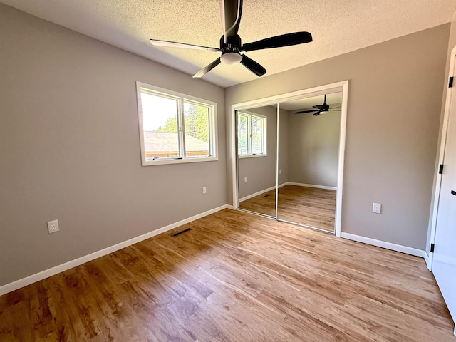 3331 Lakeshore Dr, Gladwin, MI 48624 - unfurnished bedroom featuring a textured ceiling, light wood-type flooring, a closet, and a ceiling fan