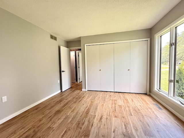3331 Lakeshore Dr, Gladwin, MI 48624 - unfurnished bedroom with wood finished floors, a textured ceiling, and a closet