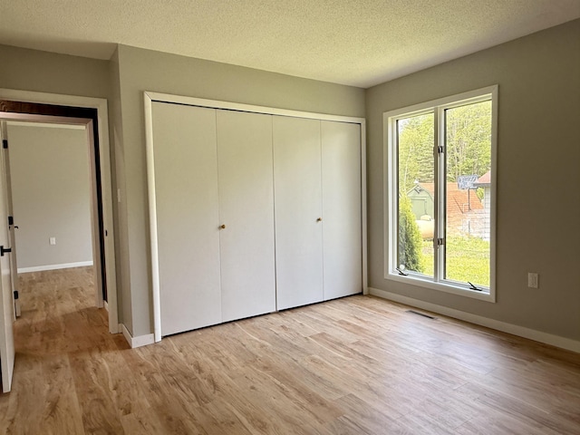 3331 Lakeshore Dr, Gladwin, MI 48624 - unfurnished bedroom with a closet, light wood-type flooring, multiple windows, and a textured ceiling