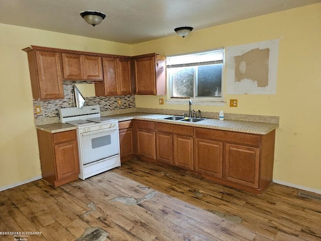 7251 Studebaker Ave, Warren, MI 48091 - kitchen with white range with gas stovetop, light wood-style floors, brown cabinetry, and light countertops