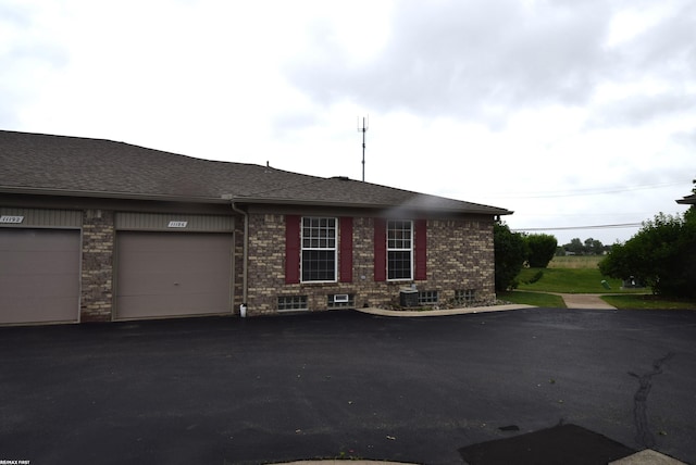 11186 Spruce Ct Unit 105, Washington Twp, MI 48094 - view of side of property featuring asphalt driveway, brick siding, a garage, and roof with shingles