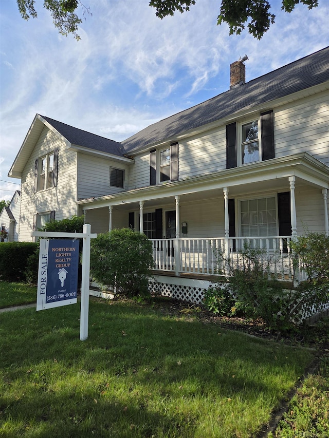 321 Lamson St, Grand Ledge, MI 48837 - farmhouse featuring a porch, a front lawn, and a chimney