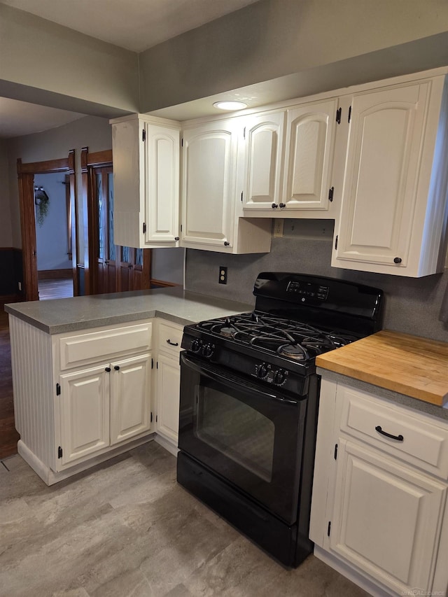 321 Lamson St, Grand Ledge, MI 48837 - kitchen with black gas range oven, white cabinetry, and a peninsula