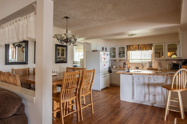 38114 Huron Pointe Dr, Harrison Twp, MI 48045 - kitchen featuring freestanding refrigerator, a textured ceiling, glass insert cabinets, dark wood-type flooring, and a chandelier