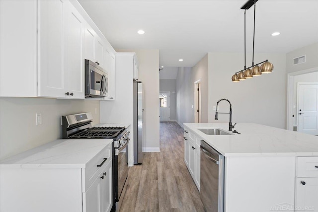27633 Maryjane Ln E, Chesterfield Twp, MI 48047 - kitchen featuring appliances with stainless steel finishes, light wood-type flooring, white cabinetry, an island with sink, and pendant lighting