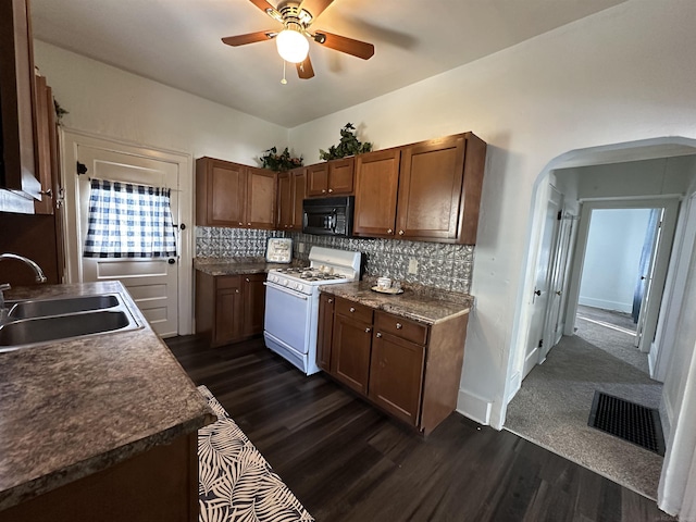 734 Court St, Port Huron, MI 48060 - kitchen with white range with gas cooktop, black microwave, arched walkways, a ceiling fan, and dark wood-type flooring