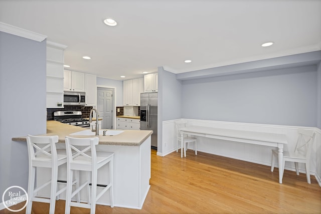 870 Crescent Ln, Grosse Pointe Woods, MI 48236 - kitchen with appliances with stainless steel finishes, a peninsula, white cabinetry, light countertops, and backsplash