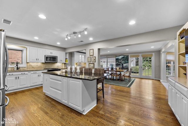 388 Lincoln Rd, Grosse Pointe, MI 48230 - kitchen with stainless steel appliances, white cabinets, dark wood-type flooring, a kitchen bar, and a kitchen island