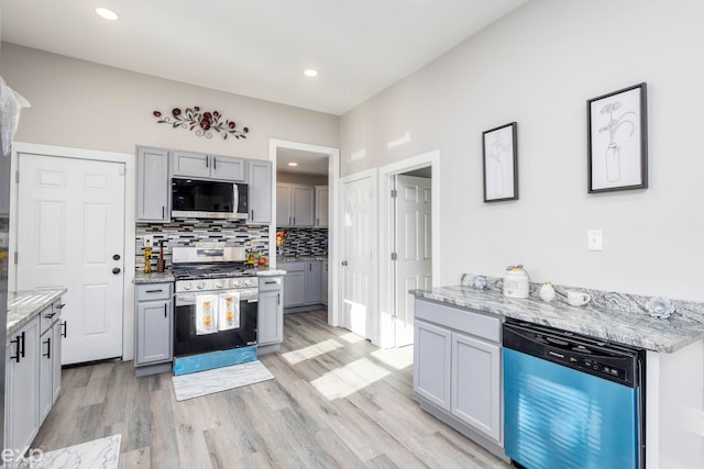 2513 Concord St, Detroit, MI 48207 - kitchen featuring stainless steel appliances, decorative backsplash, gray cabinets, light wood-style flooring, and light stone counters