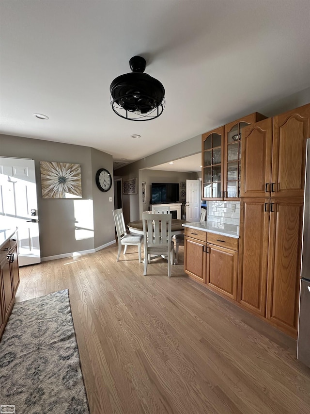 2100 Michigan St, Algonac, MI 48001 - kitchen featuring light wood-style floors, brown cabinets, glass insert cabinets, light countertops, and freestanding refrigerator