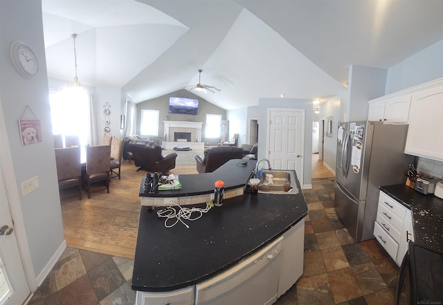 11639 State Rd, Nunica, MI 49448 - kitchen featuring a kitchen island with sink, dark countertops, a fireplace, vaulted ceiling, and stone tile floors