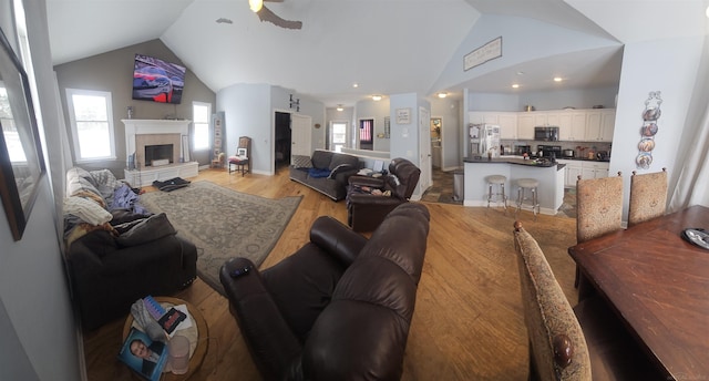 11639 State Rd, Nunica, MI 49448 - living area featuring vaulted ceiling, light wood-style flooring, a ceiling fan, and a fireplace with raised hearth