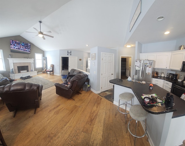 11639 State Rd, Nunica, MI 49448 - living area with a ceiling fan, vaulted ceiling, wood finished floors, a fireplace with raised hearth, and recessed lighting