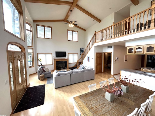 10125 Saint John Dr, Algonac, MI 48001 - living room with high vaulted ceiling, a glass covered fireplace, beamed ceiling, a ceiling fan, and light wood-style floors