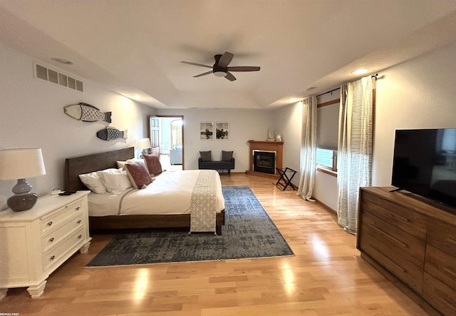 10125 Saint John Dr, Algonac, MI 48001 - bedroom with light wood finished floors, ceiling fan, a glass covered fireplace, and a raised ceiling