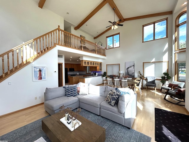 10125 Saint John Dr, Algonac, MI 48001 - living area featuring a ceiling fan, beamed ceiling, light wood-style flooring, high vaulted ceiling, and stairs
