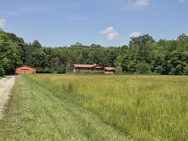 55305 Fairchild Rd, Macomb, MI 48042 - view of yard with a forest view, dirt driveway, a garage, and a view of countryside