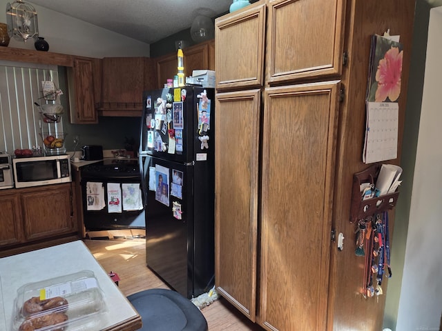 55305 Fairchild Rd, Macomb, MI 48042 - kitchen with freestanding refrigerator, stainless steel microwave, range, light wood-style floors, and lofted ceiling