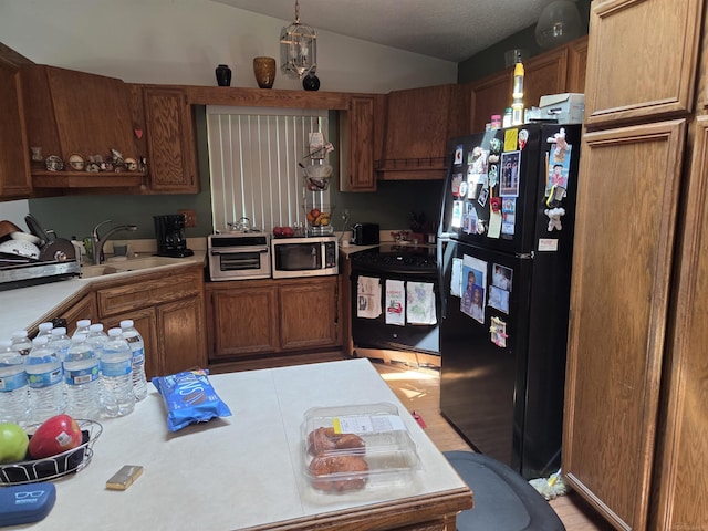55305 Fairchild Rd, Macomb, MI 48042 - kitchen with black appliances, light countertops, vaulted ceiling, and brown cabinetry