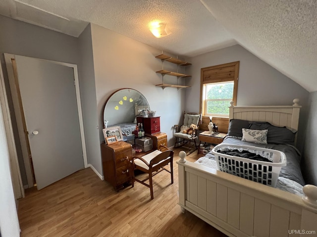 608 W Onota St, Munising, MI 49862 - bedroom featuring a textured ceiling, light wood-style floors, and lofted ceiling