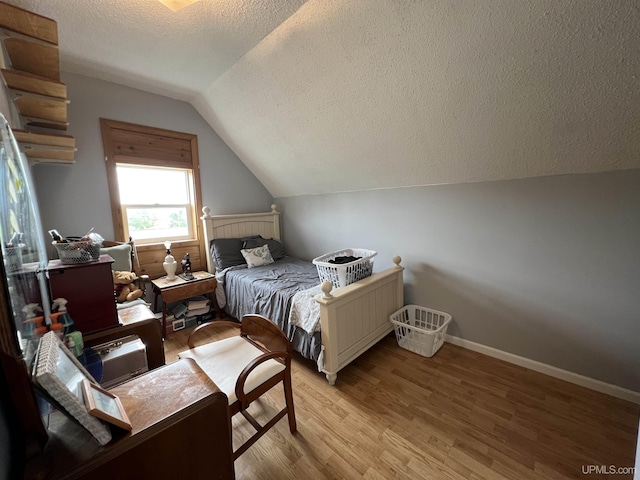 608 W Onota St, Munising, MI 49862 - bedroom featuring vaulted ceiling, light wood-type flooring, and a textured ceiling