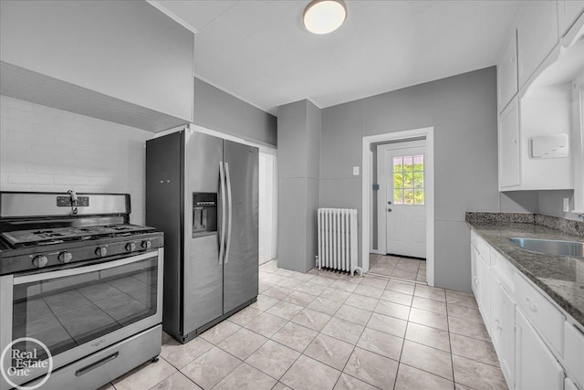 1118 Bancroft St, Port Huron, MI 48060 - kitchen featuring appliances with stainless steel finishes, radiator, white cabinetry, dark stone countertops, and light tile patterned flooring