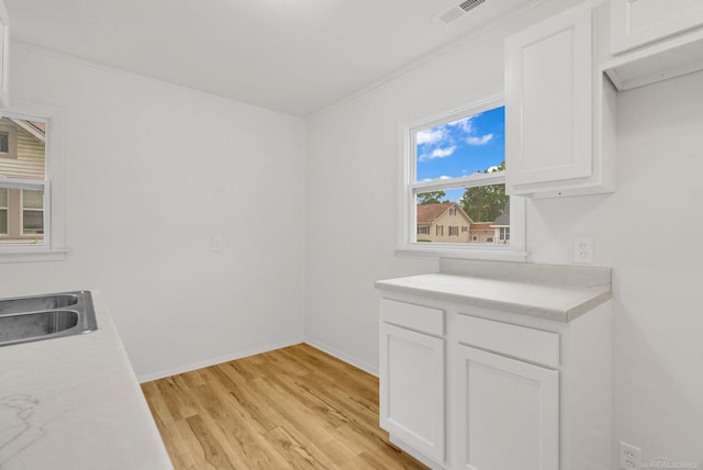 1404 Pine St, Port Huron, MI 48060 - kitchen with light wood-type flooring, white cabinets, light countertops, and ornamental molding