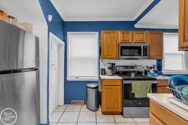 2019 Griswold St, Port Huron, MI 48060 - kitchen featuring appliances with stainless steel finishes, light countertops, brown cabinetry, light tile patterned floors, and ornamental molding