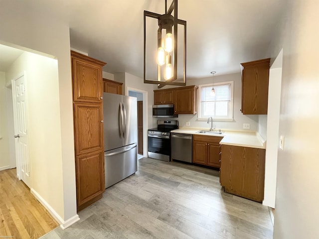 26315 Ursuline St, Saint Clair Shores, MI 48081 - kitchen featuring appliances with stainless steel finishes, light wood-type flooring, brown cabinets, and decorative light fixtures