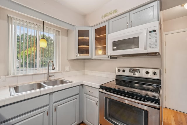 6575 Goldfinch Ln, Clarkston, MI 48346 - kitchen featuring stainless steel electric stove, white microwave, glass insert cabinets, and pendant lighting