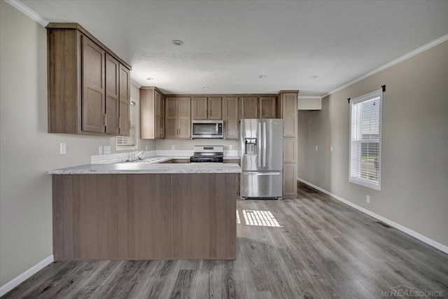 260 Meadow Ln, Port Huron, MI 48060 - kitchen featuring appliances with stainless steel finishes, ornamental molding, wood finished floors, light countertops, and a peninsula