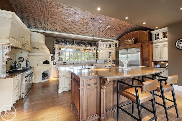 5350 Brewster Rd, Oakland Twp, MI 48306 - kitchen featuring built in refrigerator, a large island, vaulted ceiling, brick ceiling, and light wood finished floors