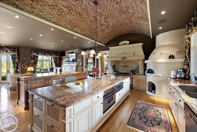 5350 Brewster Rd, Oakland Twp, MI 48306 - kitchen with a large island, cream cabinets, light wood-style flooring, stainless steel appliances, and lofted ceiling