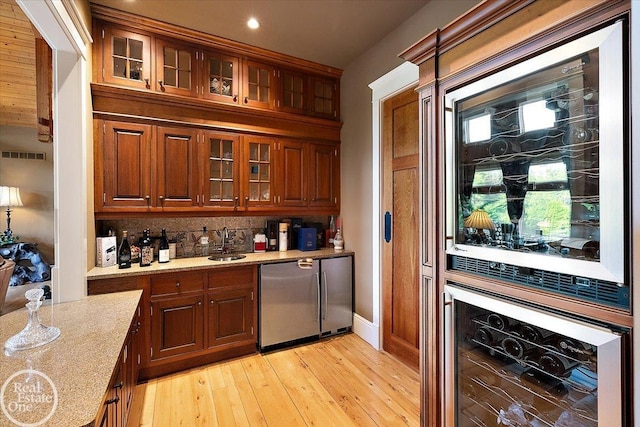 5350 Brewster Rd, Oakland Twp, MI 48306 - indoor wet bar featuring beverage cooler, decorative backsplash, light wood-style floors, fridge, and recessed lighting