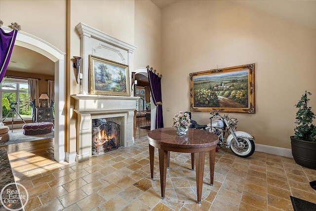 5350 Brewster Rd, Oakland Twp, MI 48306 - living room featuring arched walkways, a premium fireplace, stone tile floors, and a towering ceiling